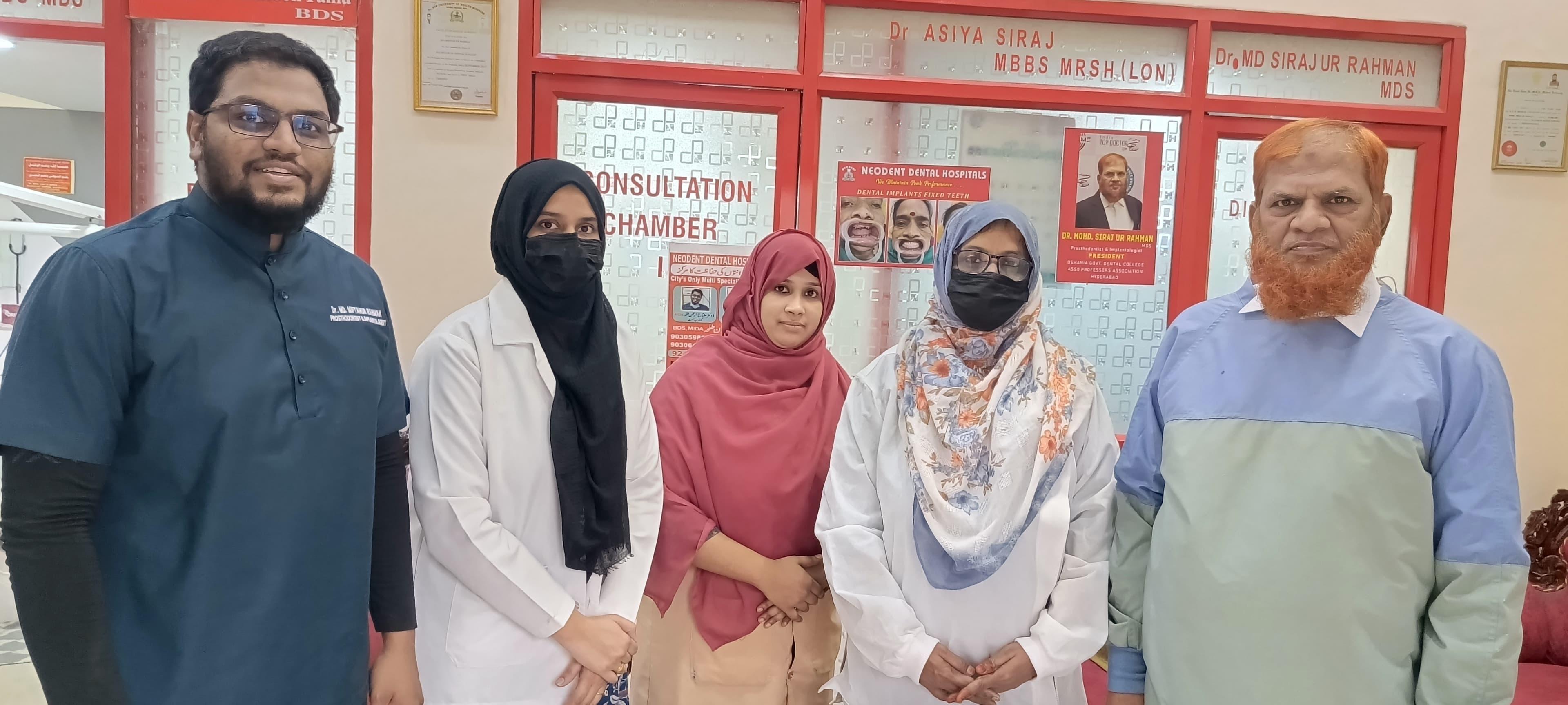 Five people in clinical attire standing together in front of red-framed consultation chamber doors at Neodent Dental Hospitals